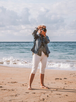 woman in casual clothes takes pictures on the beach