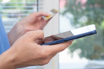 A woman makes purchases, pays bills online using a smartphone. Selective focus on the hand, tinting.