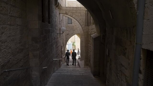 People walking down the Via Dolorosa, a processional route in the Old City of Jerusalem, slow motion static shot.
