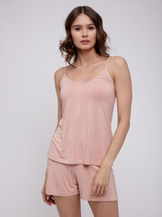 Obraz premium High fashion photo of a beautiful elegant young woman in a pretty peach beige nightgown, top, shorts posing over white background. Slim figure. Studio Shot. Pastel 