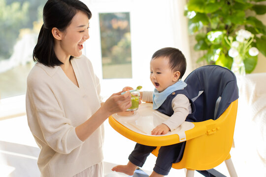 Young mother feeding baby at home - Powered by Adobe