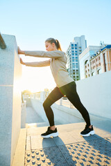 Side view of young blond sportswoman in activewear holding by bridge fence while doing physical exercise in urban environment