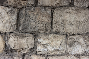 Old stone wall. Old masonry of irregularly shaped stones.