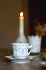 Cup of tea, plate with chocolate chip cookies, open book, reading glasses, lit candles and dry lavender flowers. Hygge at home, selective focus.