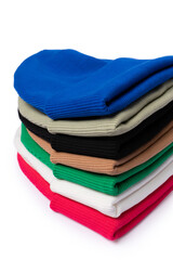 Close up of stack of insulated stylish beanie hats in bright colors isolated on white. Vertical photo