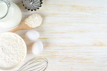 Fototapeta na wymiar Baking cooking Ingredients background with copy space. Flour, eggs, milk, bakeware on white wooden surface. Top view, flat lay. Mockup menu, banner, header for site, baking concept