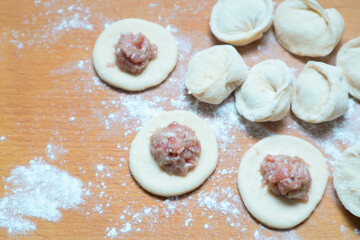 Dumplings with meat. Vareniki Homemade. Flour, dough on a wodden background. Home cooking dumplings, dough and minced meat