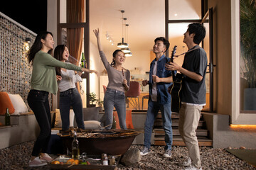 Happy young friends barbecuing outdoors