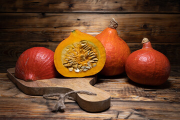 Hokkaido pumpkins on wooden background. Red kuri squash autumn fall rustic composition for...