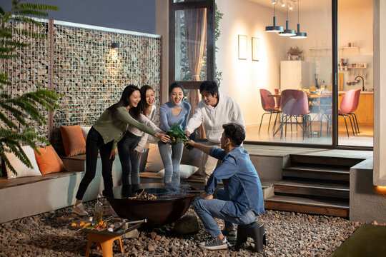 Happy young friends barbecuing outdoors - Powered by Adobe