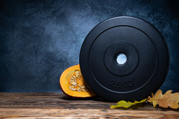 Dumbbell barbell weight plate with Hokkaido pumpkin and autumn leaves. Healthy fitness lifestyle...