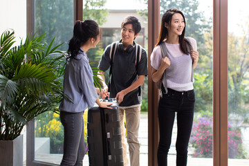 Happy young couple entering hotel room with suitcase