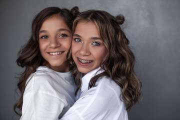 Portrait of two beautiful girls teenagers hugging and posing  with light make-up