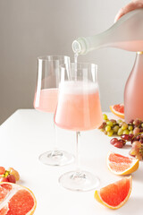 Pouring sparkling rose grapefruit alcoholic wine from a bottle into a glass