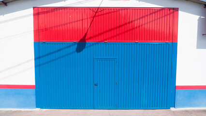 Sombra de farola en puerta metálica azul y roja