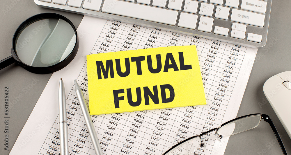 Poster mutual fund text written on a sticky on chart with keyboard and magnifier