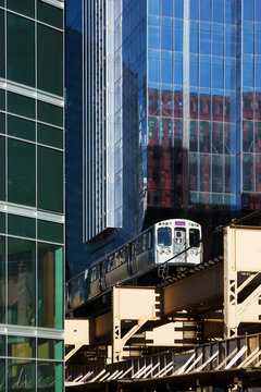 Train in transit on elevated railway between modern buildings of the downtown, Chicago.
