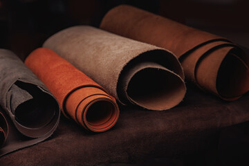 Different rolls of multi-colored natural color leather dark background. Materials for production...