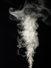 Fluffy white smoke on a black background, swirls and rises upwards as an abstract effect