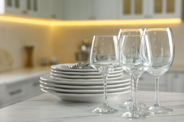 Clean glasses, dishware and cutlery on white marble table in kitchen