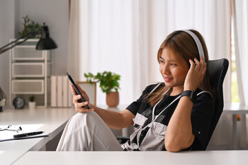 Happy young woman wearing wireless headphone spending free time at home and enjoying favourites song