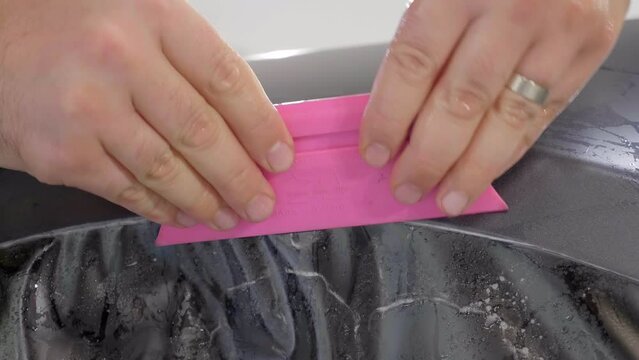 Applying Pressure to Car Wrapping Foil with a Squeegee Tool, Close Up.