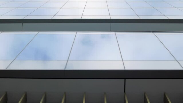Looking up at modern glass office building with reflective curtain wall and large glass window panels
