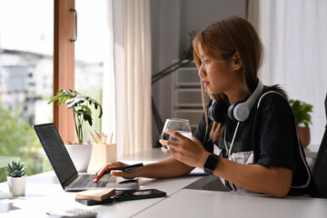 Young asian woman remote work or online education via laptop at home. Freelance, business, creative occupation concept