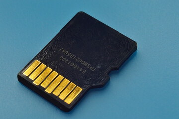 a micro sd flash drive lies on a blue background with the contacts facing up