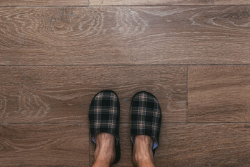 Man wearing home slippers standing on the bathroom floor tiles, top down perspective