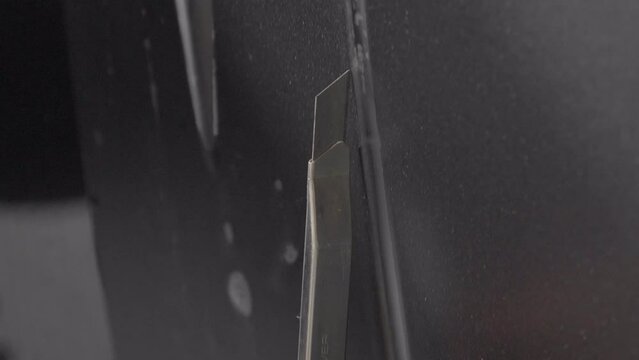 Tracking Shot of Knife's Blade Cutting in Car Wrapping Foil, Close Up.