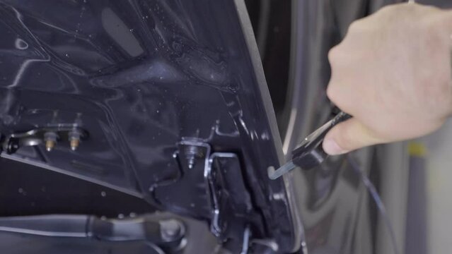 Mechanic Using Heat Blower on Vinyl Foil Applied to Car's Hood.