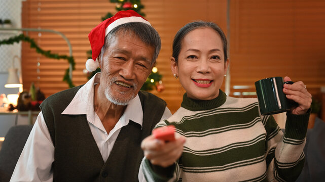 Happy senior couple enjoy watching television, spending leisure time together in winter weekend. Holidays, leisure and people concept 