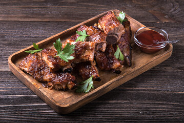 Barbecue pork ribs on a wooden table with sauce.