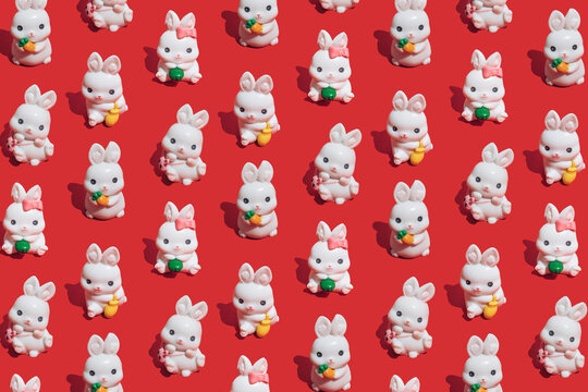 Seamless pattern made of little white rabbits on vibrant red background. Symbol of the Chinese New Year of the rabbit. Happy 2023 and good luck!