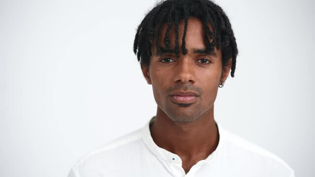 Face of concentrated African man with dreadlocks opening eyes at camera in the white studio