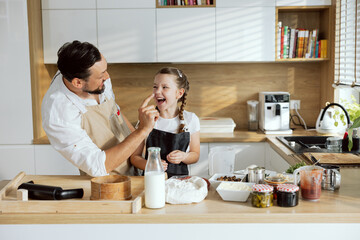 Delighted father touching daughter's nose laughing spending time together on modern kitchen. Family...