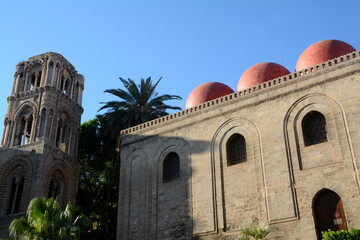 Fototapeta na wymiar Italy – Palermo – July 15, 2022:The red domes of the church of San Cataldo in Byzantine and Arab-Norman architecture near the Martorana in Piazza Bellini and Palermo skyline.