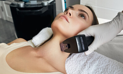 Pretty woman getting rf-lifting for her neck and body. Rf lifting procedure at beauty parlour with...