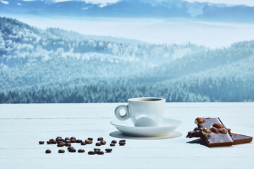 Cup of delicious coffee on snowy surface over mountain background