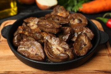 Frying pan with delicious kidneys on wooden board, closeup