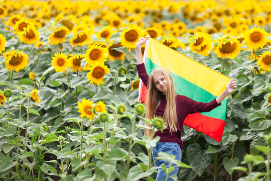 Girl holding flag of Lithuania in a sunflowers field. Lithuanian Flag Day. Independence restoration Day. Travel and love Lithuania concept. Selective focus.