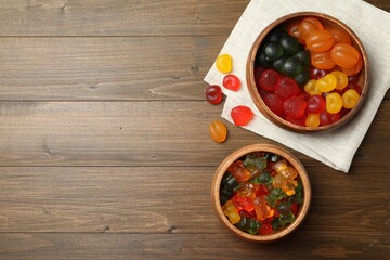 Delicious gummy candies on wooden table, flat lay. Space for text