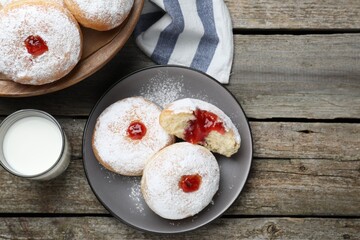 Delicious jelly donuts served with milk on wooden table, flat lay