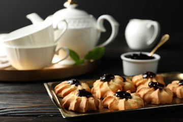 Tasty shortbread cookies with jam on black wooden table