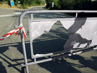 Broken barricade with striped ribbon on road