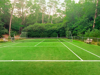 Tennis court with green grass and net outdoors