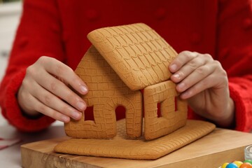 Woman in red sweater making gingerbread house, closeup