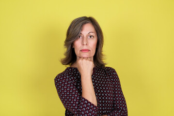 Studio portrait of an attractive 50 year old woman on yellow background