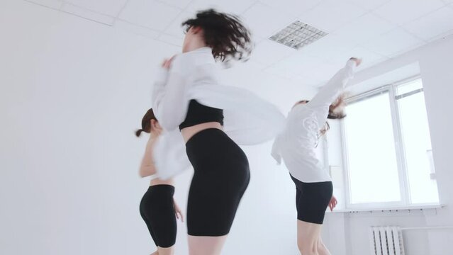 Three young girls rehearse in the studio and use parallel and asynchronous movements in modern dance